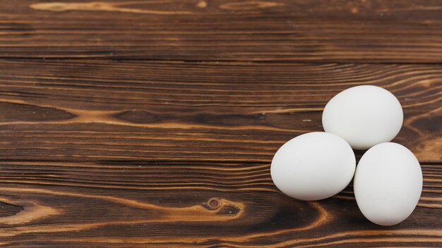 Drie witte eieren op houten tafel