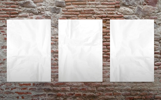 Gratis foto drie witte posters in een bakstenen muur