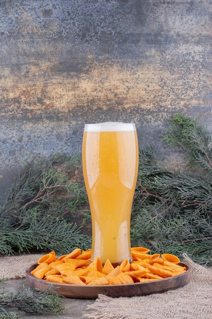 Driehoekige chips en glas bier op houten plaat. Hoge kwaliteit foto