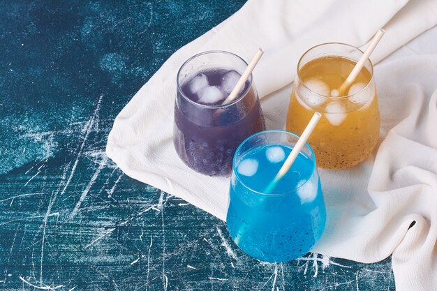 Drievoudige kleurenbekers drank op blauw.