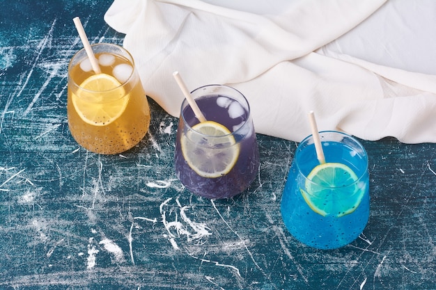 Drinkbekers in drie verschillende kleuren op blauw.