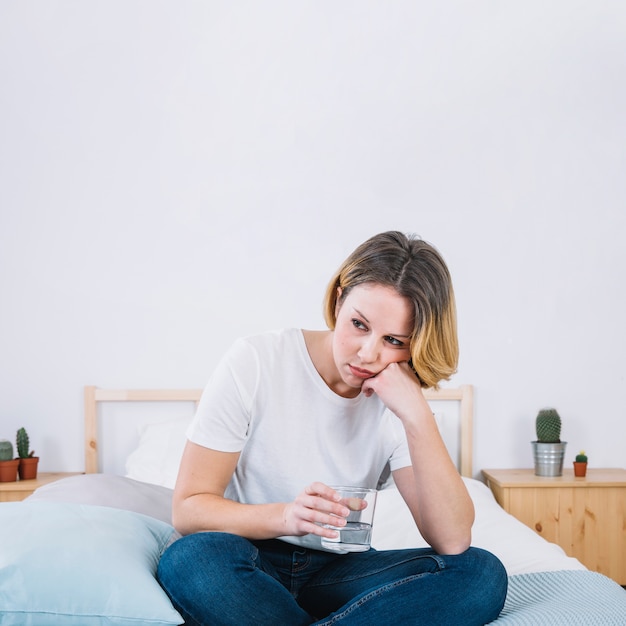 Droevige vrouw met water op bed