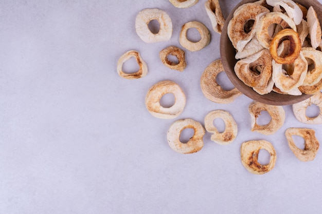 Droge appelschijfjes in een houten beker op een grijze ondergrond