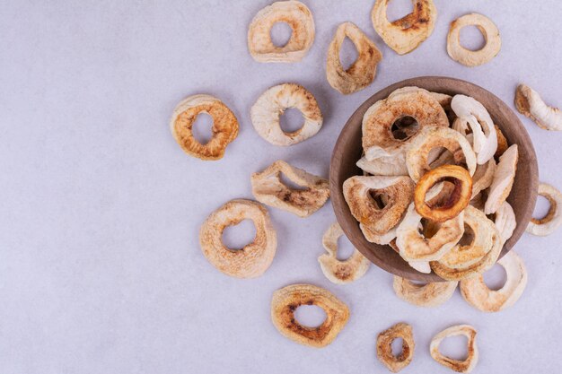 Droge appelschijfjes in een houten beker op een grijze ondergrond