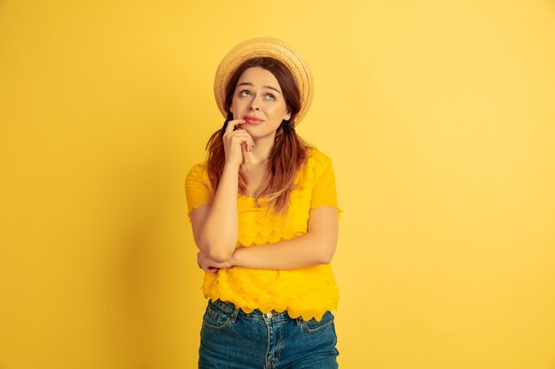 Dromerig, attent. Kaukasische vrouw portret op gele studio