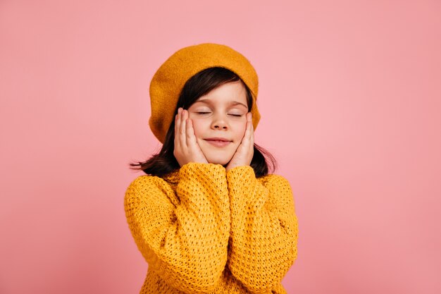 Dromerig kind poseren met gesloten ogen. zorgeloze jongen geïsoleerd op roze muur.