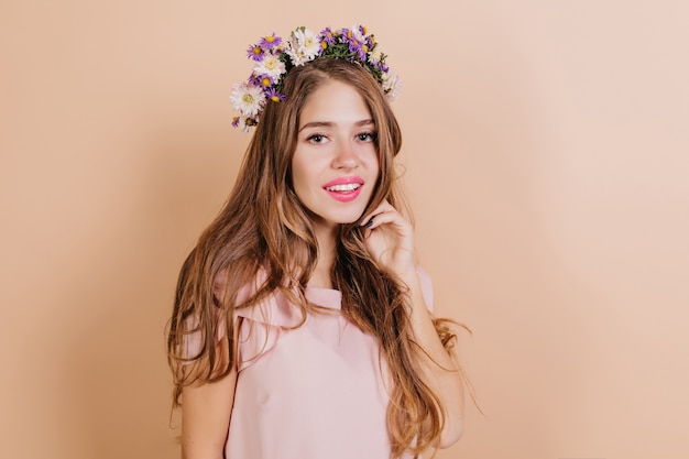 Dromerige langharige brunette vrouw met paarse bloemen in haar glimlachen naar de camera