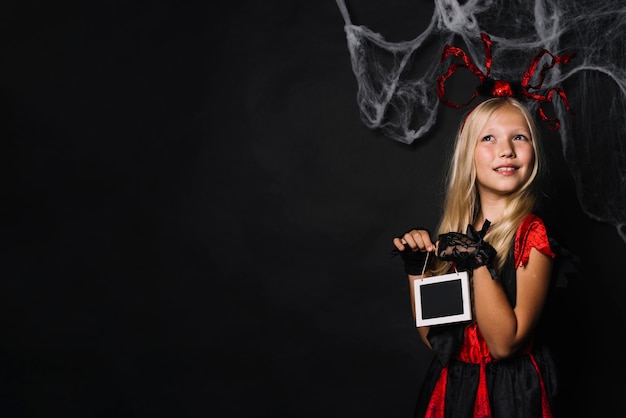 Dromerige meisje in Halloween kostuum houden schoolbord