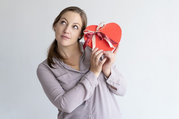 Dromerige mooie vrouw die rode hart gevormde geschenkdoos