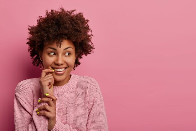 Dromerige positieve vrouw kijkt opzij, heeft een tedere glimlach, witte tanden