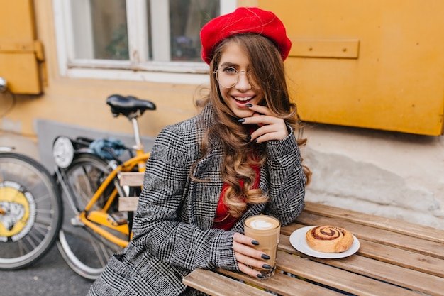 Dromerige vrouw die na het fietsen van koffie en cake geniet