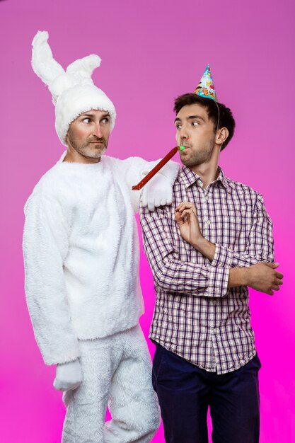 Dronken man en konijn op verjaardagsfeestje over paarse muur.
