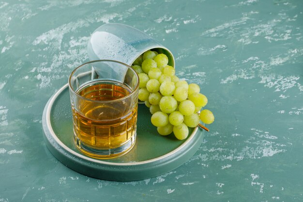 Druiven met drankje in een kopje op gips en lade achtergrond, hoge hoekmening.