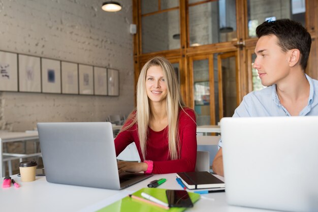 Drukke jonge man en vrouw die op laptop in open ruimte co-working kantoorruimte werkt