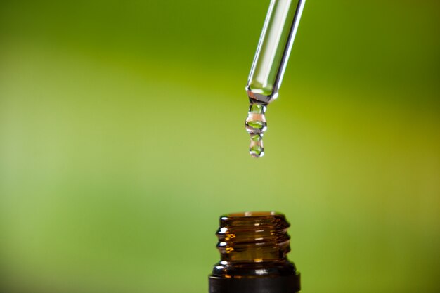 Druppel olie druipend van pipet in fles essentiële olie