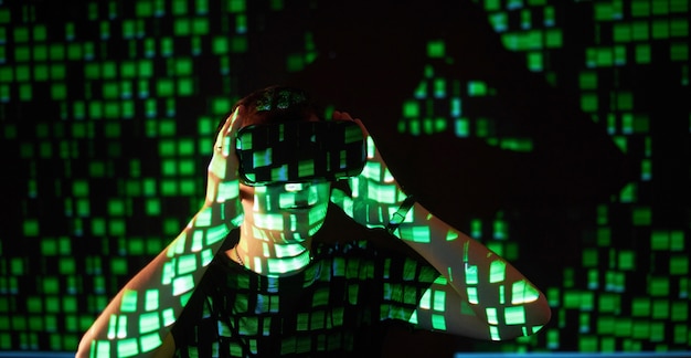 Dubbele belichting van een blanke man en een virtual reality vr-headset is vermoedelijk een gamer of een hacker die de code kraken in een beveiligd netwerk of server, met regels code in groen