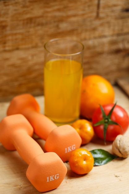 Dumbbell, sinaasappelsap, fruit en noten op de houten tafel, sport en gezondheids lifestyle concept