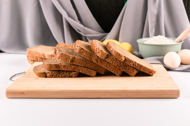 Dun gesneden donker tarwebrood op een houten bord