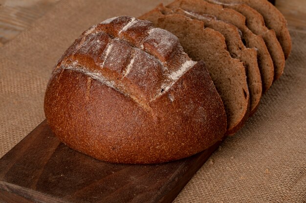 Dun gesneden roggebrood op een houten bord.