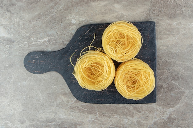 Gratis foto dunne spaghetti-nestjes op houten plank