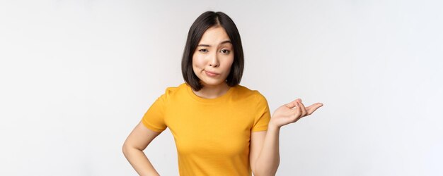 Dus wat een onbezorgde aziatische vrouw die haar schouders ophaalt en er geen idee van heeft dat ze tegen een witte achtergrond staat?