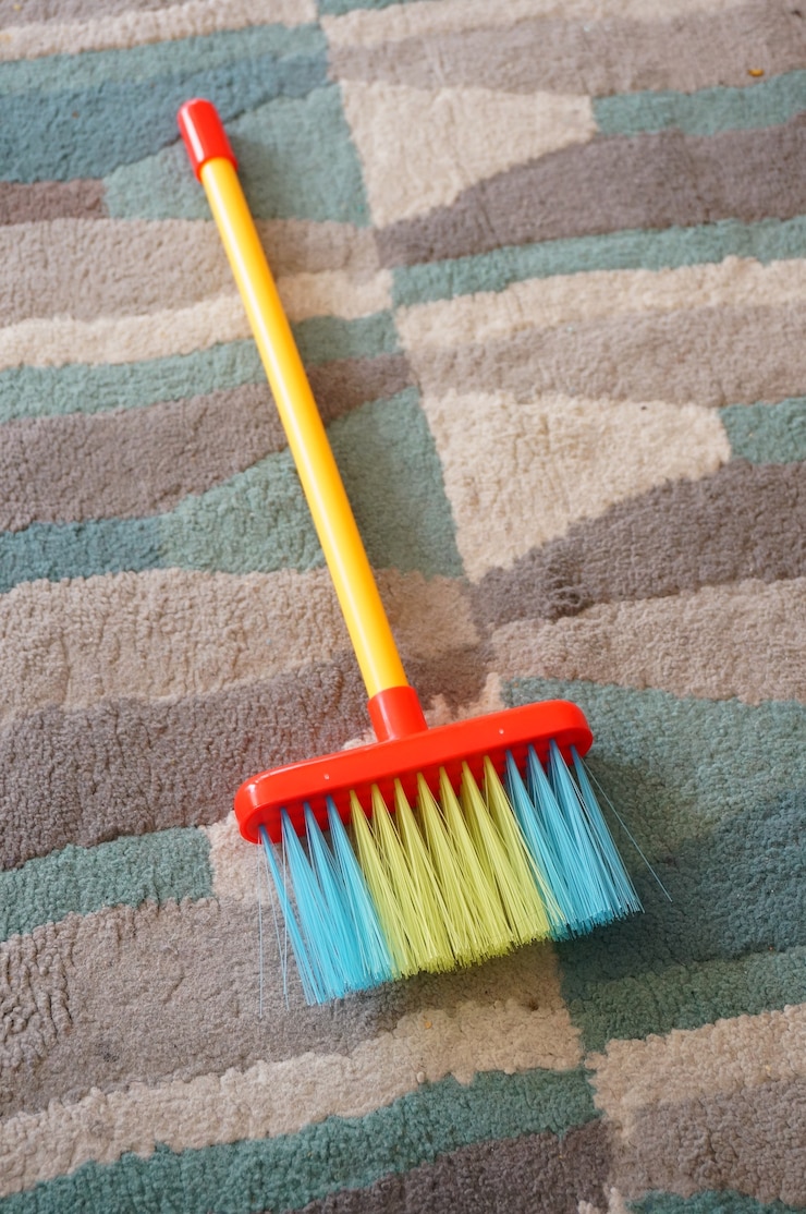 Gratis Foto duw een bezem van verschillende kleuren op een veelkleurig tapijt