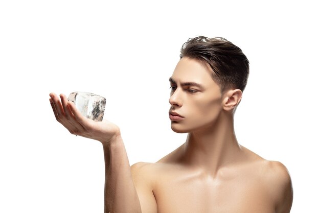Echt. Portret van een jonge man geïsoleerd op een witte studio achtergrond. Kaukasisch aantrekkelijk mannelijk model. Concept van mode en beauty, zelfzorg, lichaams- en huidverzorging. Knappe jongen met verzorgde huid.