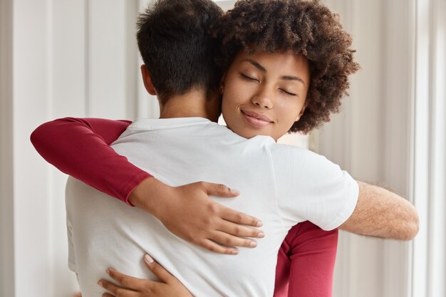 Echtgenoten omarmen liefdevol in het interieur van hun huis