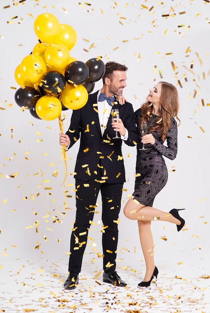 Gratis foto echtpaar met ballonnen en champagne fluit nieuwjaar vieren