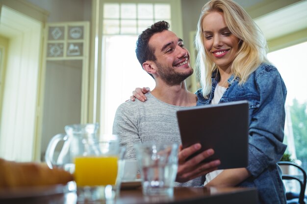 Echtpaar zitten aan tafel en met behulp van digitale tablet in cafÃ ©