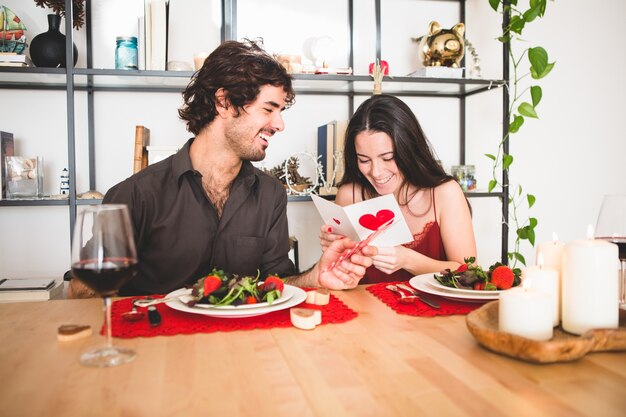 Echtpaar zittend aan een tafel te eten terwijl ze leest een romantische postkaart