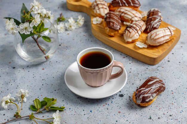 Eclairs of soesjes met zwarte chocolade en witte chocolade met vla binnen, traditioneel Frans dessert. Bovenaanzicht.