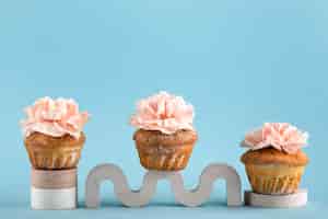 Gratis foto eco cupcakes met bloemen en blauwe achtergrond