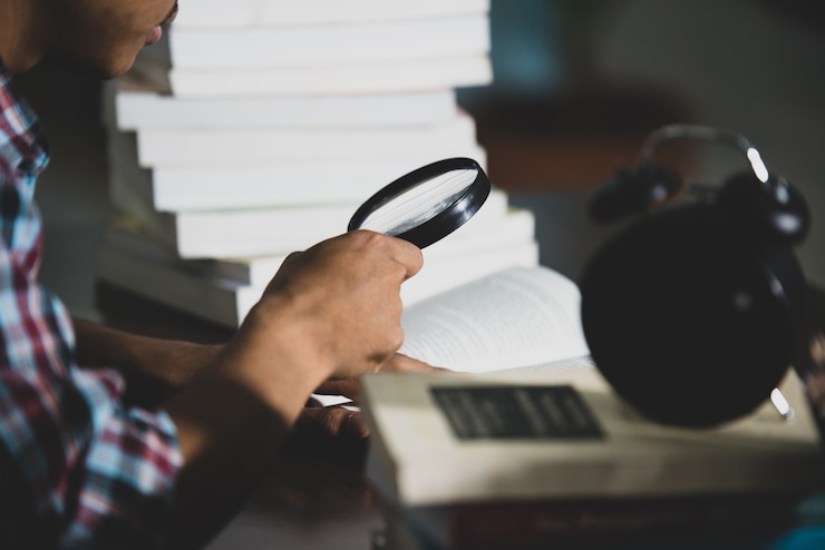 Gratis Foto educatief thema: close-up student kijkt door een vergrootglas om te boeken