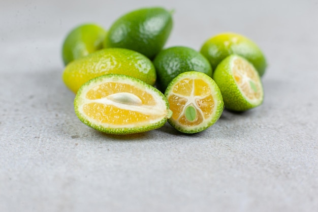 Een aantal hele en gesneden kumquats op marmeren achtergrond. Hoge kwaliteit foto