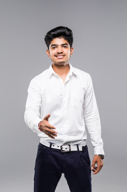 Een aantrekkelijke Indische zakenman die van hem uitbreiden deelt voor handdruk uit die op grijze muur wordt geïsoleerd