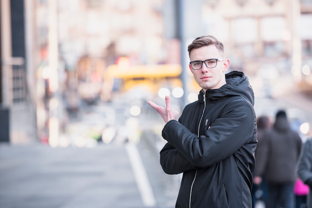 Een aantrekkelijke jonge mens die zich bij weg het gesturing bevindt