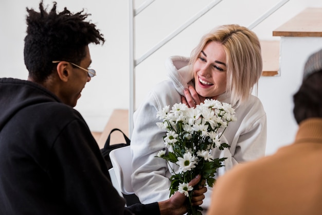 Een Afrikaanse jonge man die wit bloemenboeket geeft aan haar glimlachend meisje