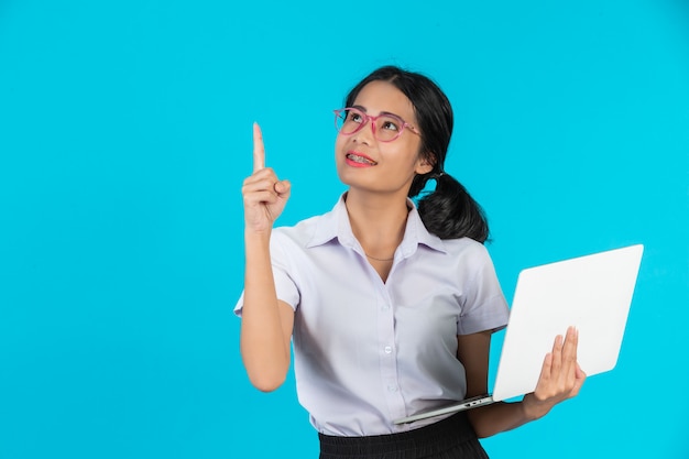 Een aziatisch studentenmeisje dat haar notitieboekje op een blauw houdt.