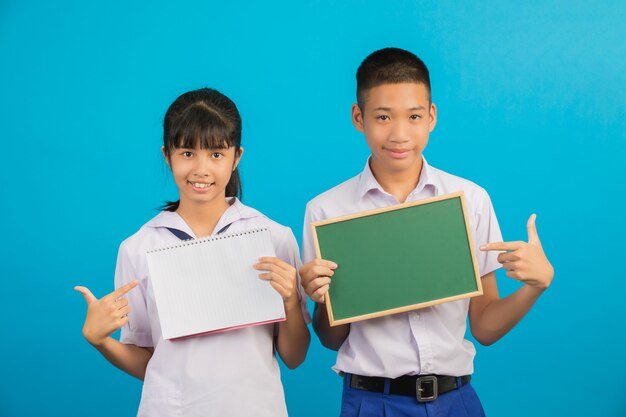 Een Aziatische student die een notitieboekje houdt en Aziatische mannelijke student die een groen raad op een blauw houdt.