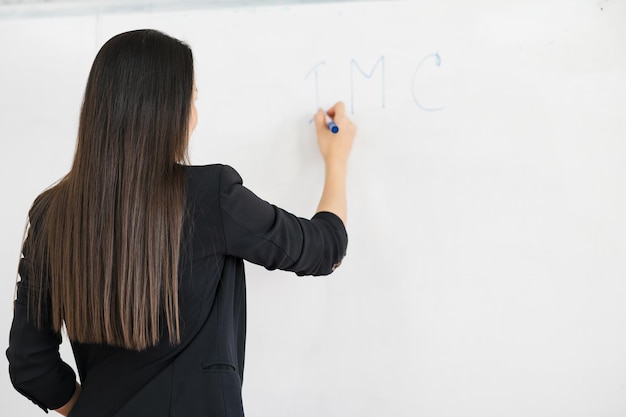 Een aziatische vrouwelijke leraar in het zwart staat voor een whiteboard voor een klaslokaal op de universiteit. onderwijsconcept, afstuderen, universitair docent caree