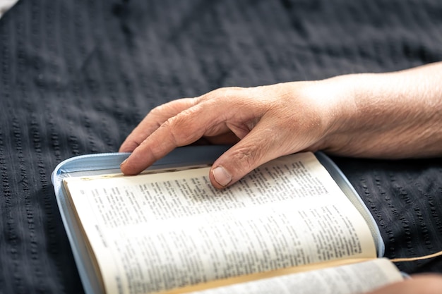 Gratis foto een bejaarde vrouw leest een boek van de bijbelhanden en close-up