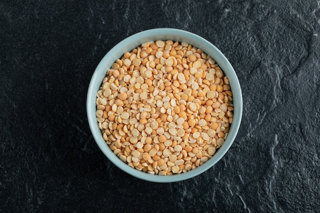 Een blauw bord met ongekookte popcorn op een donkere