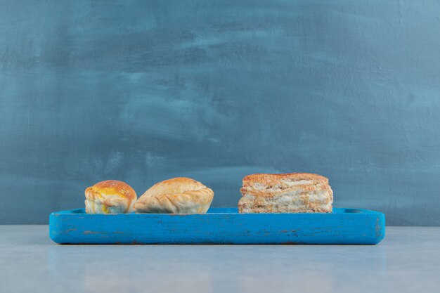Een blauwe houten plank vol zoete koekjes.