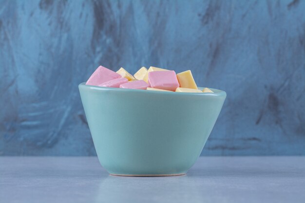Een blauwe kom vol roze en gele zoete zoetwaren Pastila. Hoge kwaliteit foto