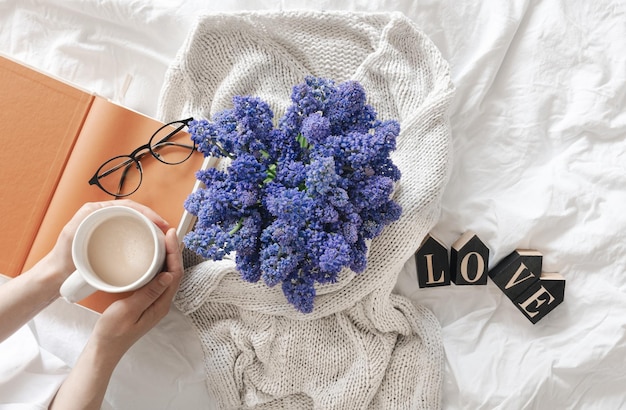 Gratis foto een boeket bloemen een kopje koffie en een decoratief woord liefde in een wit bed