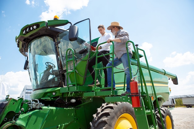 Een boer met een tractor combineert op een veld in zonlicht zelfverzekerde felle kleuren