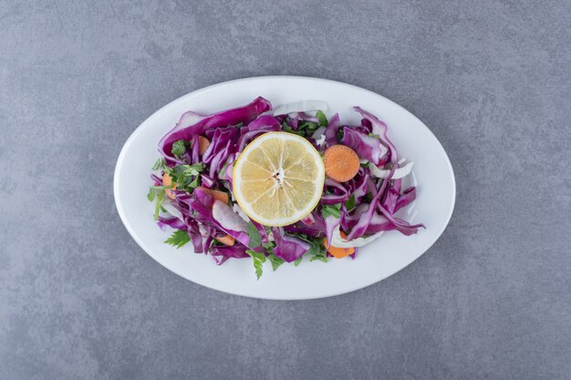 Een bord met geraspte groenten met citroen, op het marmeren oppervlak.
