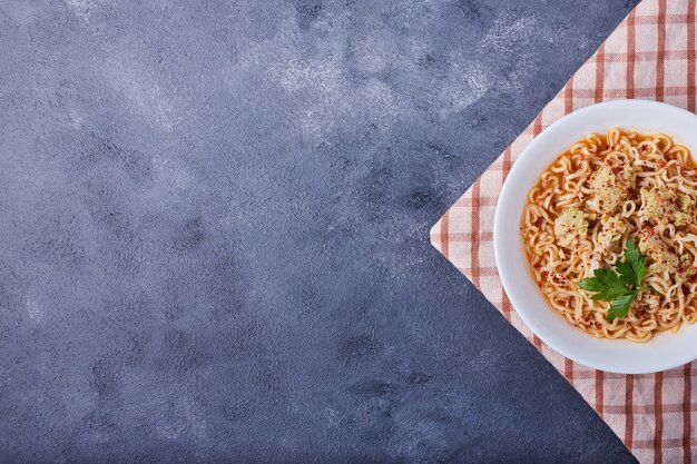 Een bord pasta op blauwe tafel met kruiden.