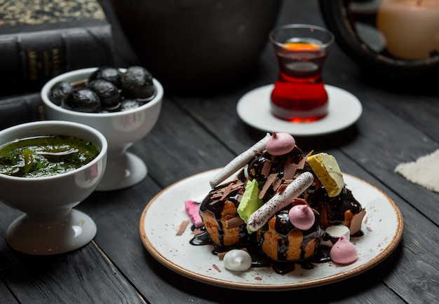 Een bord profiteroles geserveerd met chocoladesaus